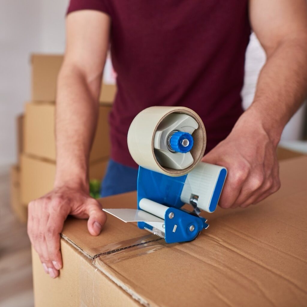 Das Bild zeigt ein Teammitglied des Umzugsservice Berlin beim Verpacken von Umzugsgut.